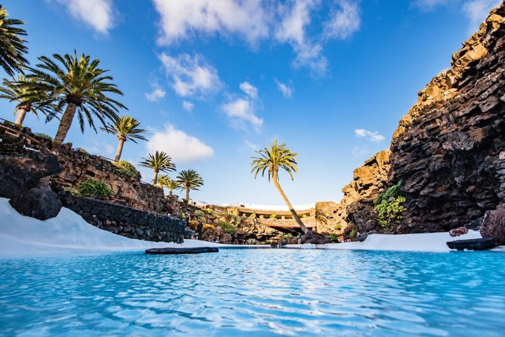 The turquoise pool of Jameos del Agua between palm trees and lava walls